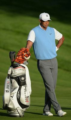 a man standing next to a golf bag on top of a green field