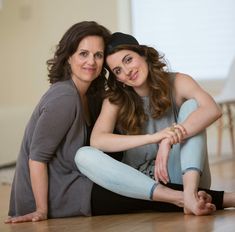 two women sitting on the floor with their arms around each other