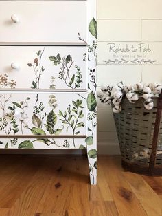 a white dresser with flowers painted on it and a basket full of cotton floss