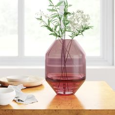 a vase with flowers in it sitting on a table next to plates and bowls,