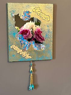 a mirror with flowers hanging from it's side next to a wall mounted clock