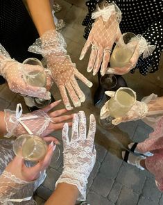 several people wearing gloves and holding wine glasses in the middle of a circle with lace on them