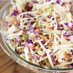 a glass bowl filled with coleslaw on top of a wooden table