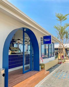 the outside of a blue and white building with an arched doorway that leads into it