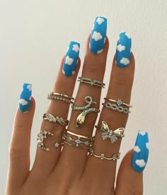 a woman's hand with blue and white manicures on it, holding five different rings