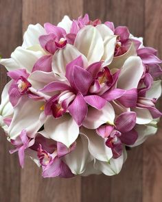 purple and white flowers in a vase on a wooden table next to a wood wall