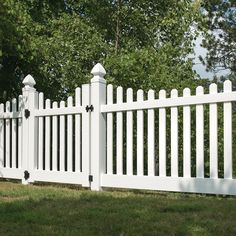 a white picket fence in front of some trees