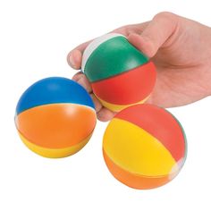 a hand is holding three balls in different colors