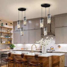 a kitchen filled with lots of counter top space and lights hanging from the ceiling above it