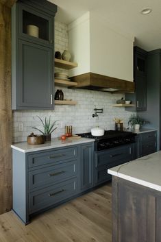 a kitchen with gray cabinets and wooden floors