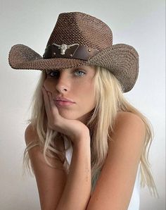 a woman wearing a cowboy hat with her hand on her chin looking at the camera