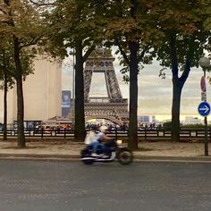 a man riding a motorcycle down the street in front of the eiffel tower