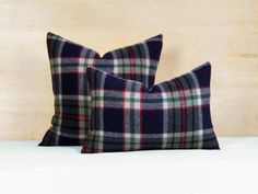 two black and white plaid pillows sitting on top of a bed next to each other