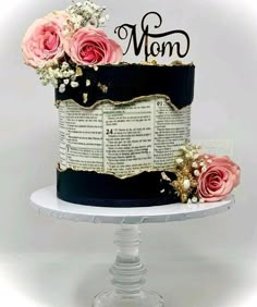 a cake decorated with pink roses and an old book is on top of a pedestal