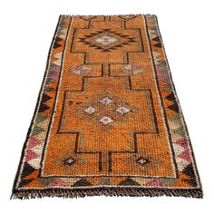 an orange and black rug with fringes on the bottom, in front of a white background