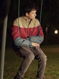 a young man sitting on a swing at night