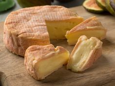 sliced cheese on a wooden cutting board with figs in the background