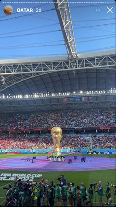 the soccer field is full of people and there is a giant trophy in the middle