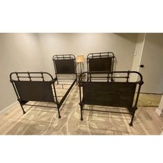 four black metal beds sitting on top of a hard wood floor next to a lamp