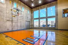 an indoor basketball court with multiple windows and lights on the ceiling, surrounded by wood flooring