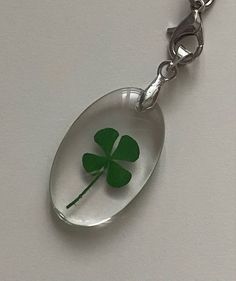 a green four leaf clover in a glass pendant on a silver chain with a white background