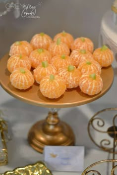 there are many small oranges on the cake platter that is ready to be eaten