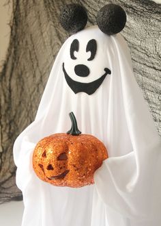 a halloween ghost holding a pumpkin in its hand with a smile on it's face