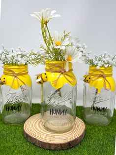 three jars with flowers in them sitting on the grass