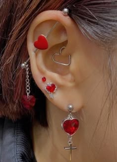 a close up of a person's ear with two hearts and a cross on it