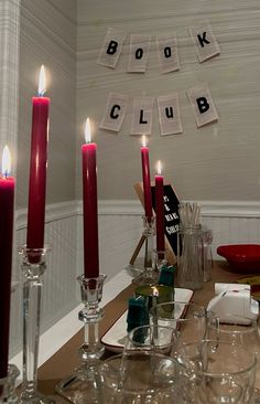 a dining room table with candles and place cards on the wall above it that says book club