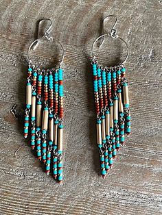 two pairs of beaded earrings on top of a wooden table