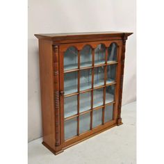 an old wooden bookcase with glass doors on the top and bottom shelves, in front of a white wall