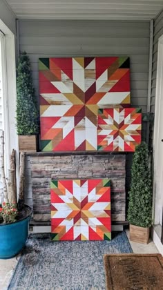 two colorful quilts are hanging on the wall next to a blue potted plant