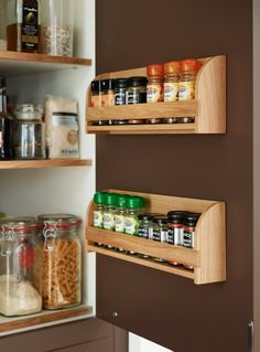 two wooden spice racks in a kitchen with spices on the shelves and seasonings on the bottom shelf