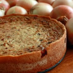 a pie sitting on top of a wooden table next to onions