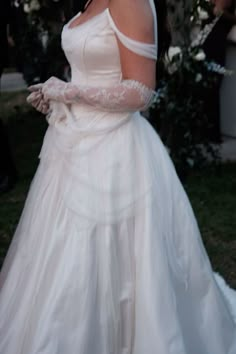 a woman in a white dress and gloves on her wedding day, posing for the camera