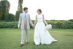 a bride and groom holding hands in the grass