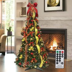 a decorated christmas tree sitting in front of a fire place with a remote control on the floor