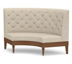 a beige couch with wooden legs and buttons