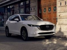 a white mazda cx - 5 parked in front of a building