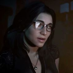 a woman wearing glasses looking at the camera in a dark room with light coming through her eyes