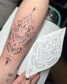 a person with a tattoo on their arm holding a white paper fan in her hand