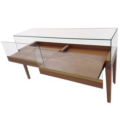 a glass and wood coffee table with an open drawer on the bottom, in front of a white background