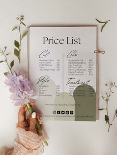 the price list is being held up by someone's hand with flowers in front of it