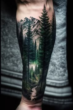 a man's arm with a forest scene on it and mountains in the background