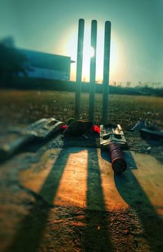 the shadow of two cricket bats on the ground