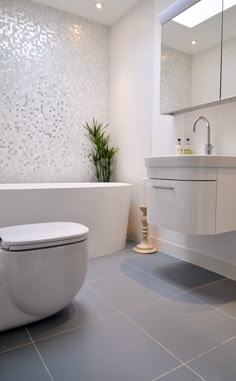 a bathroom with a toilet, sink and bathtub in the middle of it's tile flooring