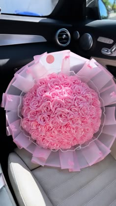 a pink flower arrangement sitting in the center of a car's steering wheel cover