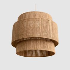 a wooden light hanging from the ceiling with a beige shade on it's side