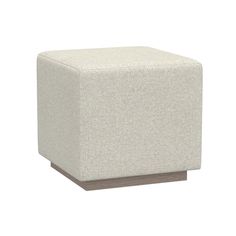 a white cube ottoman sitting on top of a wooden block